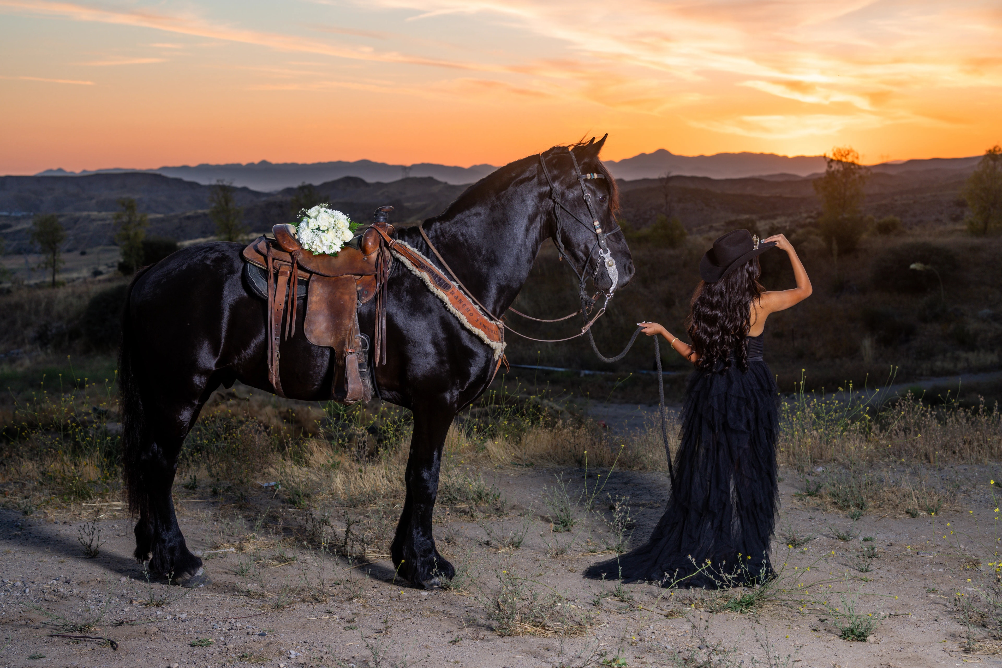 Destiny Faith Salazar beside her black horse at sunset on the ranch